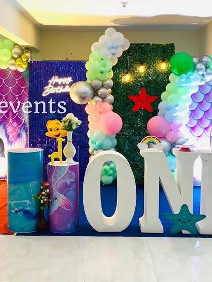 An indoor mermaid theme with a similar magical feel. This setup includes a scale-patterned backdrop, a grass wall, and large 'ONE' letters.