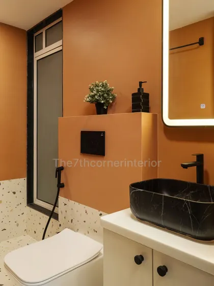 A bold and serene bathroom design where clean lines meet luxury materials. The terracotta-colored wall contrasts beautifully with the terrazzo-style tiles and the striking black marble sink.