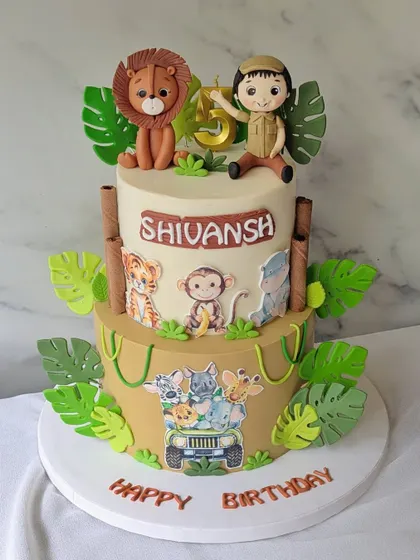 Welcome to the jungle! This two-tier safari cake is perfect for a wild 5th birthday, featuring a little explorer, a friendly lion, and lots of jungle animals.