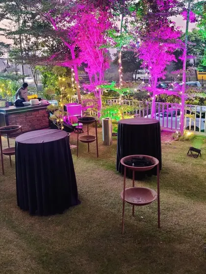 The outdoor lounge area at the corporate Christmas party. We provided black-covered cocktail tables and stools, creating a relaxed space for guests to mingle amidst the colorfully lit garden.
