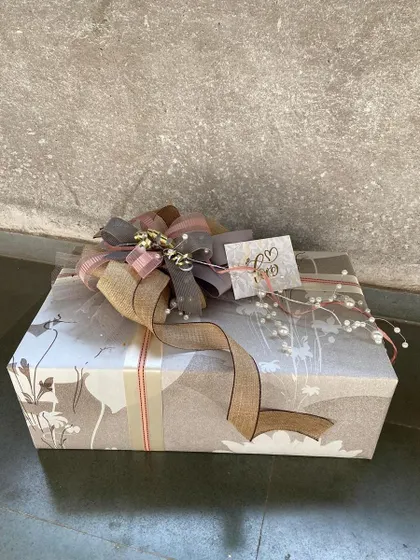 A beautifully wrapped gift box with a rustic-chic aesthetic. The nature-inspired wrapping paper is complemented by a burlap and pearl-accented bow, perfect for someone who appreciates understated elegance.