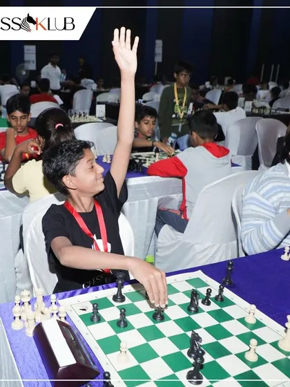 A young player raises his hand to call an arbiter, a common sight in a professionally managed Swiss system tournament.