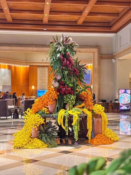 The reflection of the marigold arrangement on the polished floor adds another layer of beauty to the lobby decor.