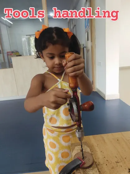 Even the youngest engineers can learn to use tools safely. This student is using a hand drill, developing motor skills and an understanding of mechanical work.
