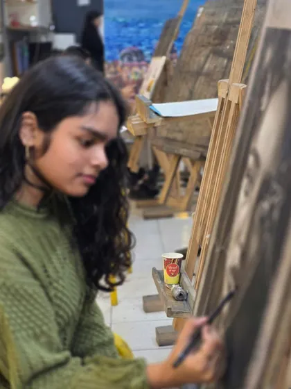 A profile shot of a young artist concentrating on her charcoal drawing, showing the focus we encourage in our students.