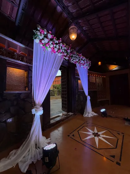 A beautiful entrance for an engagement ceremony. The combination of white drapes, pink and white flowers, and dramatic uplighting creates a magical feel.