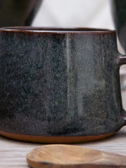A close up of a mug with our Pirate Black glaze. The subtle color variations are visible here, showing how it creates a rich, multi-tonal surface on a simple, functional form.