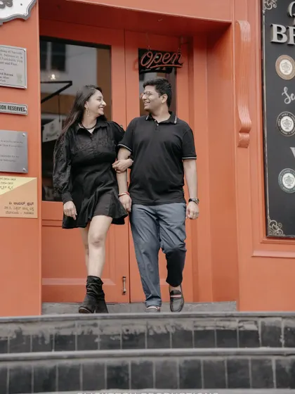 A happy couple walks down the steps of a cafe, capturing a candid and joyful moment from their urban pre-wedding shoot.