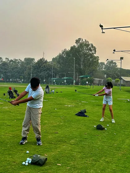 Two young golfers, a boy and a girl, practicing their swings side-by-side. It's great to see siblings and friends enjoying the game together.