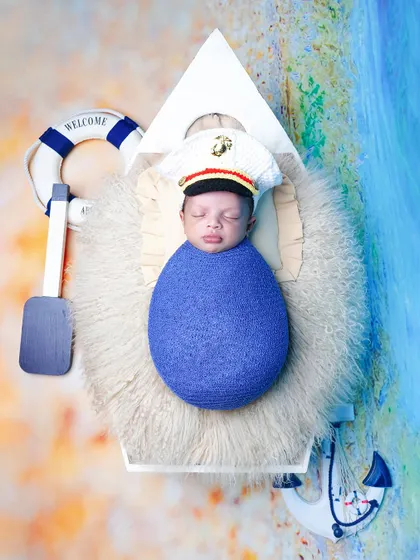 An overhead view of the nautical theme, with the baby dressed as a little captain in a boat, complete with a lifebuoy and anchor props.