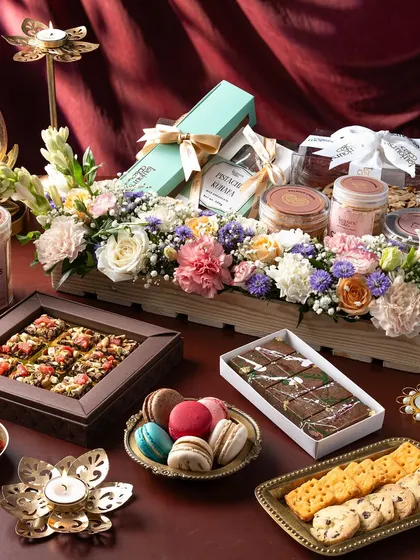 An opulent festive hamper overflowing with our artisanal creations, including beautifully packaged cookies, macarons, chocolate barks, and a stunning floral arrangement. This is the ultimate expression of thoughtful, luxurious gifting for any grand occasion.