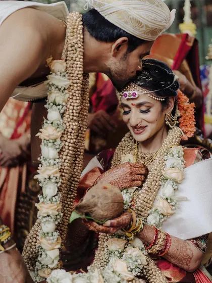 A tender kiss on the forehead from the groom is a quiet, powerful gesture of love amidst the wedding rituals. This close-up captures the emotion and connection between the couple in a deeply personal way.
