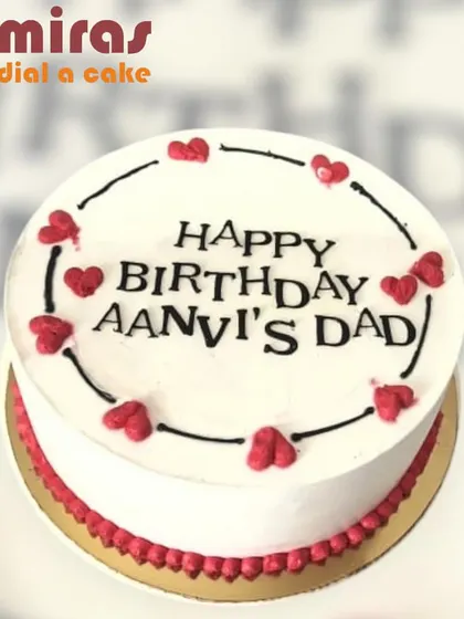 A simple and sweet birthday cake for "Aanvi's Dad." The white cake is decorated with a border of red hearts, showing that a heartfelt message is sometimes the best theme of all.