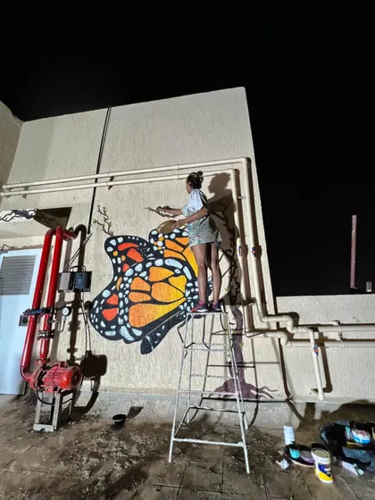 High on a ladder, adding the final touches to the butterfly's wings against the night sky.