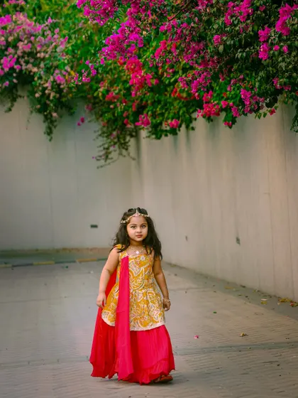 We take our studio outdoors to capture stunning portraits like this. The natural light and beautiful flowers perfectly complement this little princess in her elegant traditional dress.