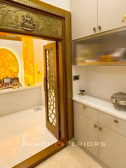 A side view of the puja room entrance, showing the seamless integration of the custom cabinetry next to the ornate doorway, providing practical storage for religious items.