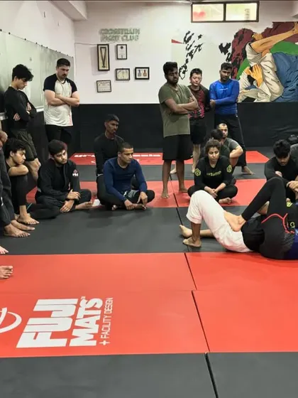 Students watch intently as a coach demonstrates a technique from the guard position. We create an environment where everyone is focused on learning and improving together.