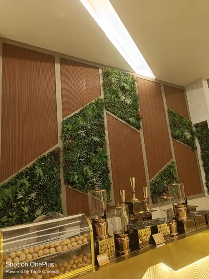For this commercial space, we integrated custom geometric green wall panels with warm wood textures. This design adds a modern, biophilic element to the interior, breaking up the monotony of a plain wall.