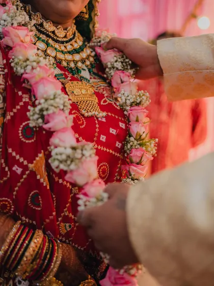 A close-up of the groom placing the floral garland on the bride during the Varmala ceremony.