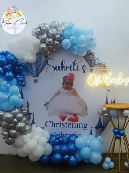 A Christening and 'Oh Baby' celebration with a custom photo backdrop and a blue, white, and silver balloon garland.
