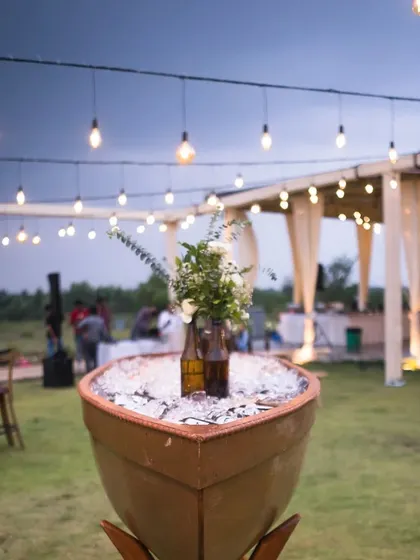 We believe in creative and sustainable decor. For this rustic Mehendi, we upcycled beer bottles into charming flower vases and used a boat as a unique centerpiece, all under a canopy of poetic string lights.