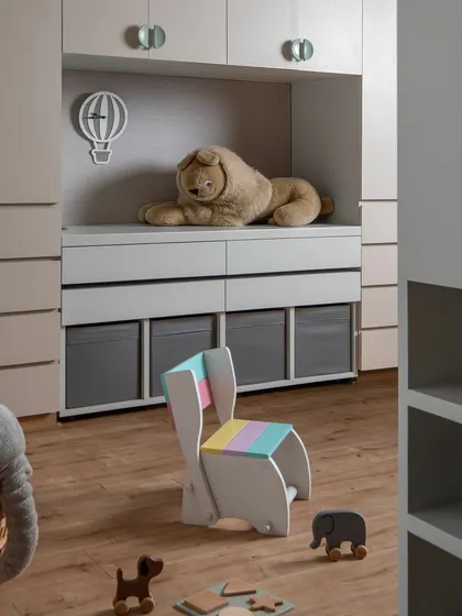 A detail of the kids' room, showing the custom storage solutions and a playful, multi-colored chair. The design is clean, functional, and leaves ample room for imagination.