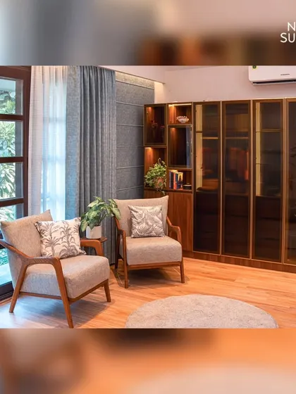 A cozy sitting nook within the eco-chic master bedroom. Two comfortable armchairs are positioned by the window, creating a perfect spot for morning coffee, complemented by a large, elegant display cabinet.