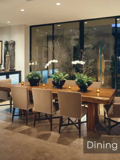 A sophisticated dining room setup with a large wooden table and comfortable upholstered chairs. The design is perfect for hosting dinner parties, with a sleek sideboard for storage and large glass doors offering a view of the outdoors.