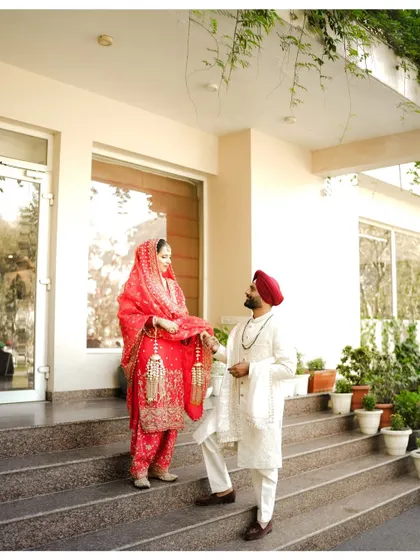 The groom playfully holds the bride's kaleeras on the steps of their Manali wedding venue. These small, candid interactions are the moments you will cherish forever.