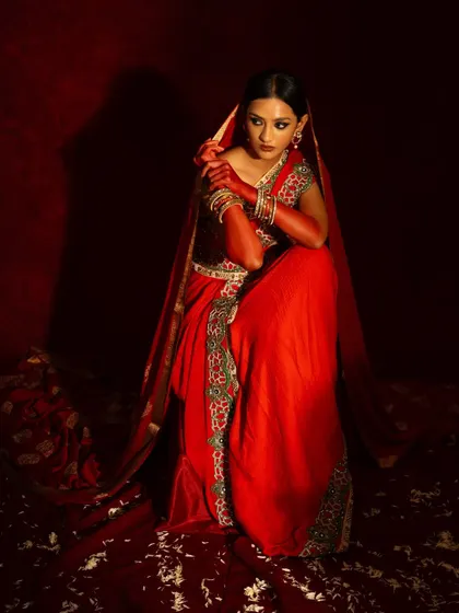 A seated portrait from the red bridal series, conveying elegance and grace. The composition is classic and perfect for a bridal lookbook.