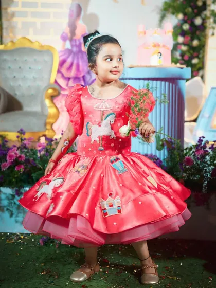 The birthday girl in her custom unicorn-themed dress, holding a white rose. Her outfit perfectly complements the whimsical and magical party atmosphere.