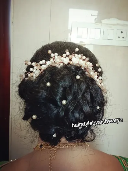 A romantic and soft messy bun. This updo is decorated with a delicate pearl and crystal hair vine, making it an ideal choice for a reception or engagement party.