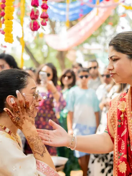 A family member lovingly applies haldi to the bride, a traditional and intimate part of the ceremony.