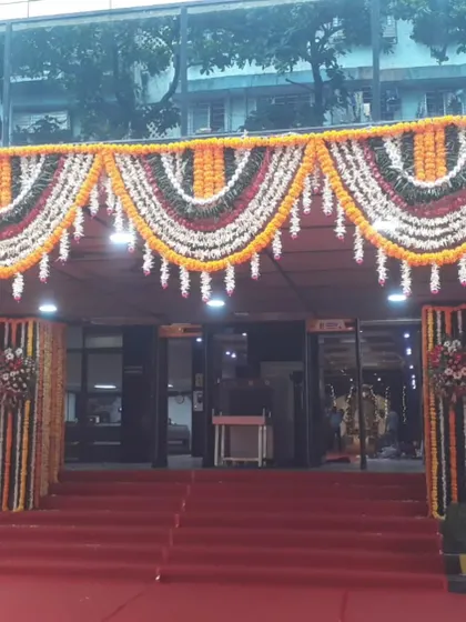The main entrance of a building in Bandra East, decorated with large garlands of marigold flowers for a festive or cultural event.