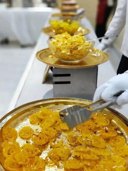 A server carefully arranging freshly made jalebis on a golden platter. We pay attention to every detail, ensuring our food is both delicious and beautifully presented.