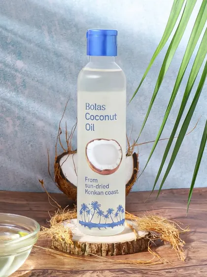 A tropical and refreshing setup for coconut oil from the Konkan coast. The blue background, palm leaves, and natural fibers evoke a coastal vibe, reinforcing the product's source.