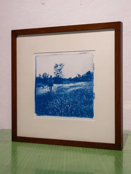 A duplicate of the framed cyanotype print of a figure in a field. The solid wood frame and classic matting enhance the timeless, handcrafted quality of the artwork.