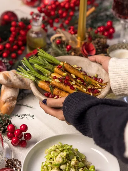 Sharing is at the heart of every celebration. A dish of honey-glazed carrots with pomegranate seeds is passed around the table, part of our communal Holiday Feast.