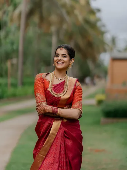 A smile that lights up the day. This candid bridal portrait captures the bride's infectious happiness and natural beauty in her stunning red saree.