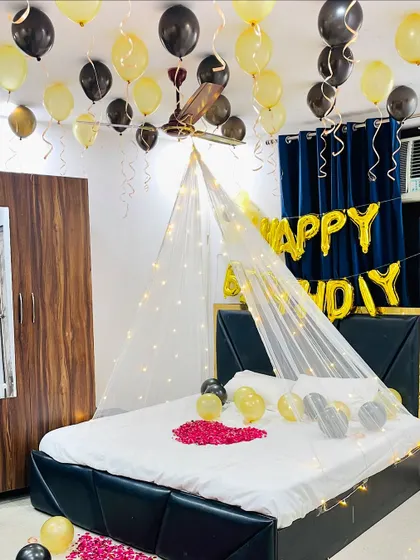 This photo shows the complete black and gold birthday setup, including balloons on the floor and a pathway of rose petals.