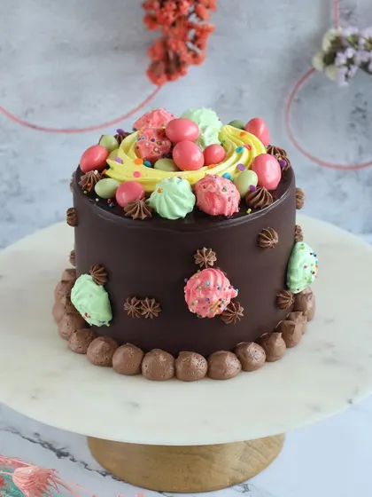A special Easter mini cake, decorated with colorful meringues and candy eggs. It's a rich chocolate cake perfect for a small family celebration.