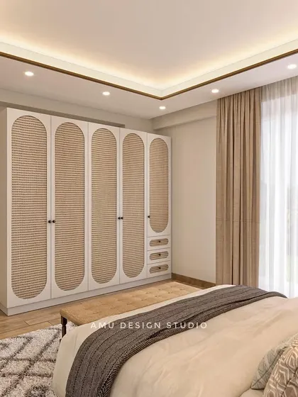 This bedroom concept shows a custom wardrobe with arched, cane-paneled doors, paired with a large, simple mirror to create a sense of space and light.