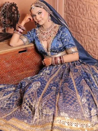 A relaxed, regal pose in the blue Banarasi lehenga, highlighting its rich texture and intricate gold weaving.