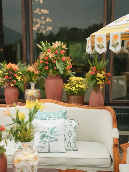 An artful composition of the lounge seating, showing the layers of decor from the floral arrangements to the custom cushions and umbrella.