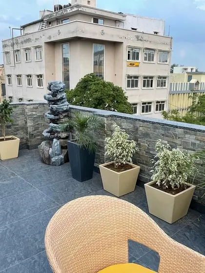 A rooftop terrace I designed for a commercial building in Ashok Vihar. The space includes a mix of potted plants, a stone-clad feature wall, and a water fountain, turning an empty roof into a relaxing retreat.