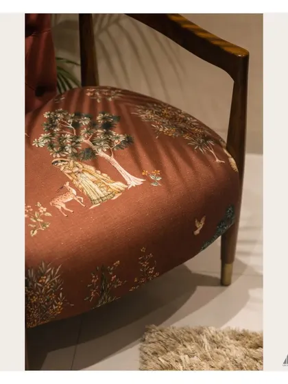 The fabric of the accent chair features a delicate woodland scene, a storytelling element that adds a layer of charm and sophistication to the bedroom's decor.
