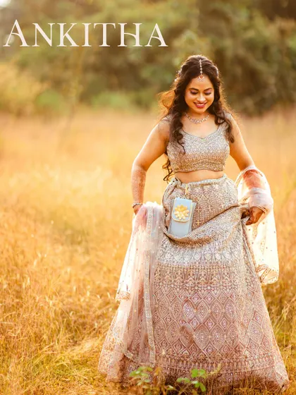 A beautiful solo portrait of the bride in a sparkling lehenga, walking through a field of tall, golden grass. The warm sunlight gives the image a dreamy, romantic glow.