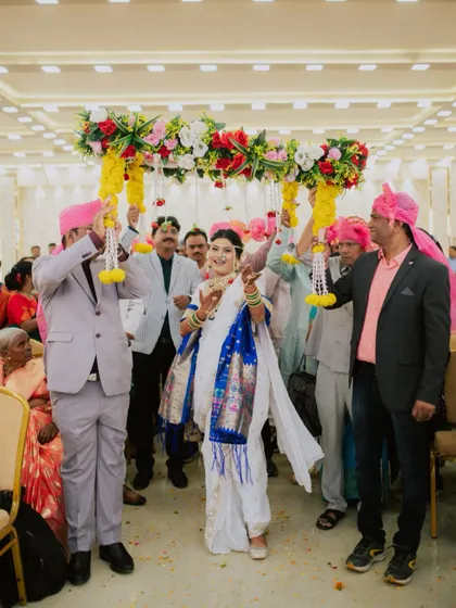 The bride's joyful entrance under a floral canopy, a beautiful moment in a Maharashtrian wedding.