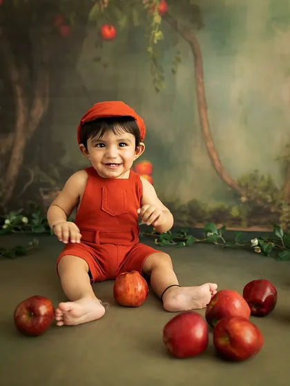 A big, happy grin. This 8-month-old is clearly enjoying his time in our whimsical, woodland-themed apple setup.