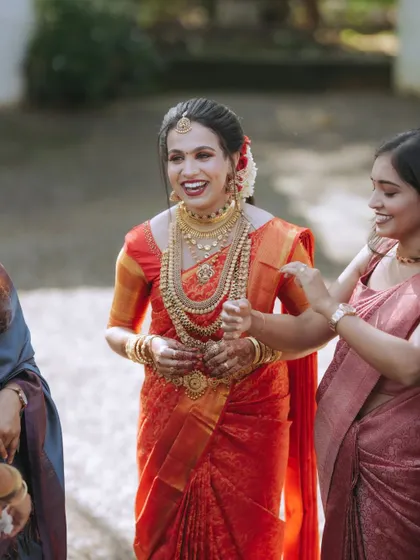 A candid shot of a bride in a stunning red silk saree, sharing a laugh with her loved ones. These unposed interactions are the memories that truly last.